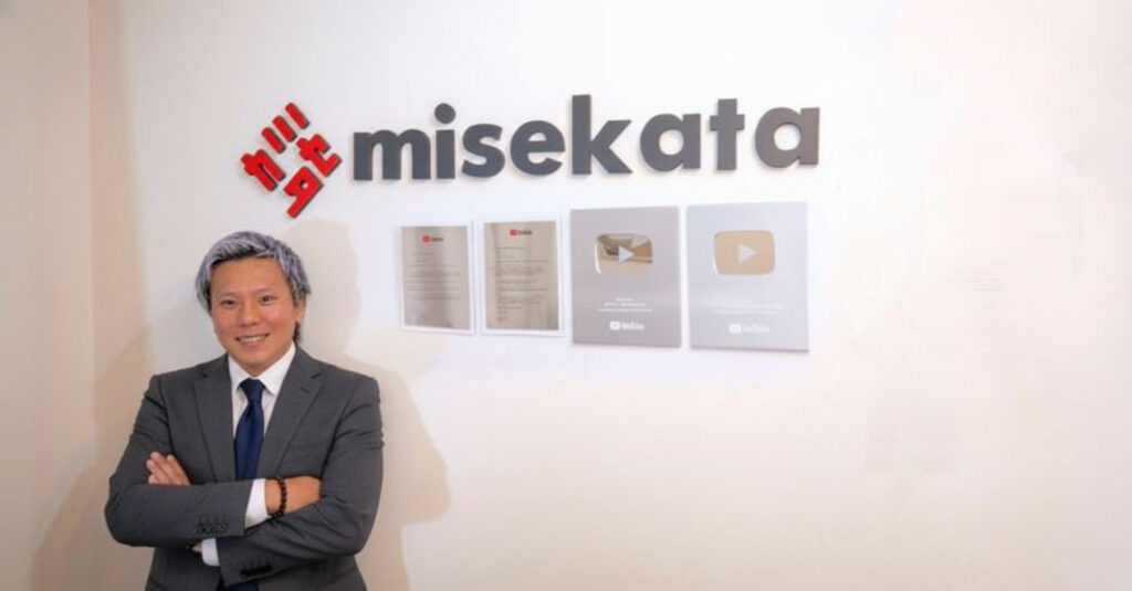 諸藤健太郎専務 銀の盾の前で写真を撮る